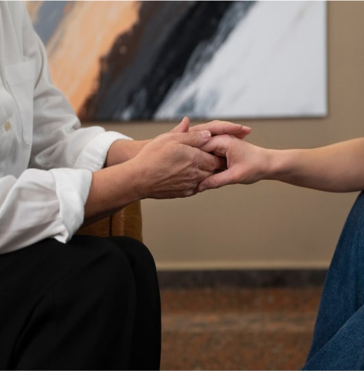 Mental health specialist holding a patient’s hand during a supportive conversation.
