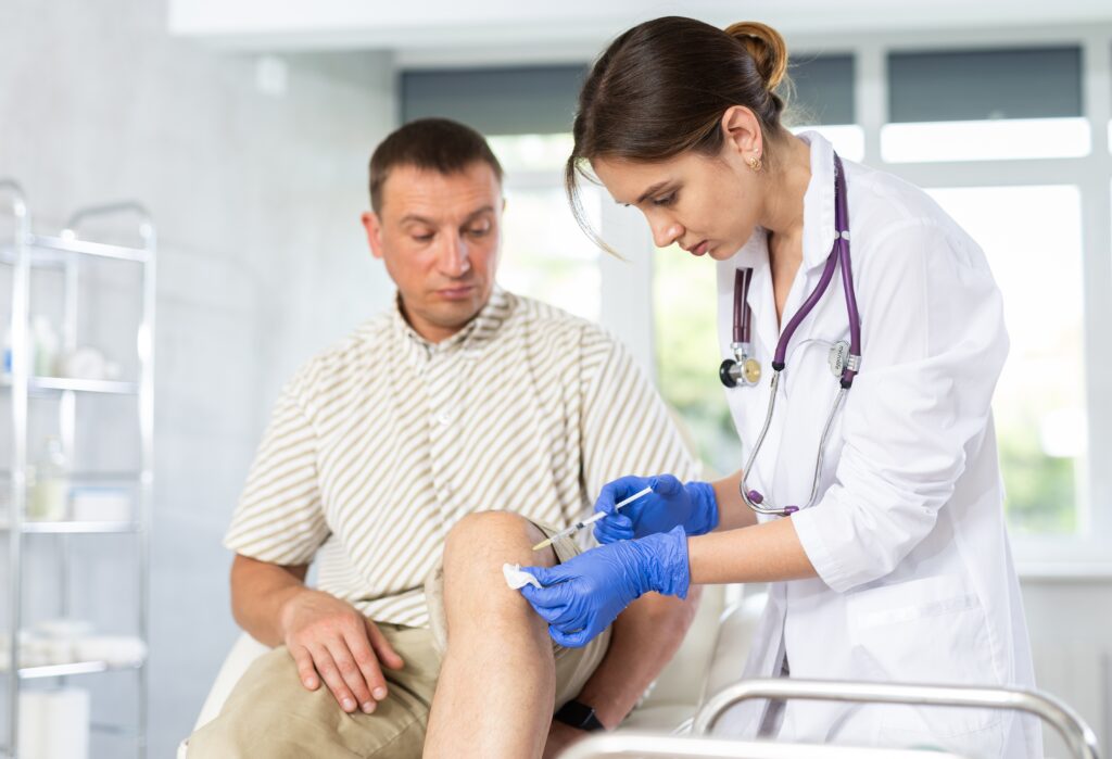 Young,female,doctor,performs,intra-articular,injection,treatment,of,knee,bursitis