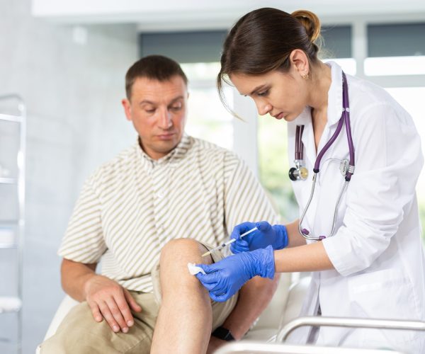 Young,Female,Doctor,Performs,Intra-articular,Injection,Treatment,Of,Knee,Bursitis