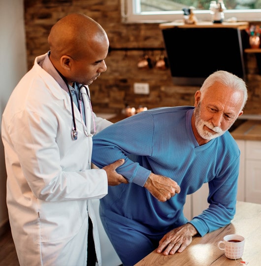 Doctor assisting an older man in pain while helping him sit up.
