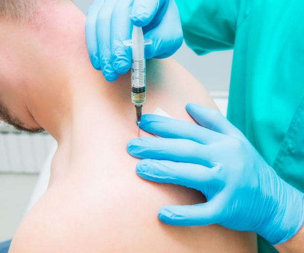 Doctor giving a close-up injection therapy (blockade)