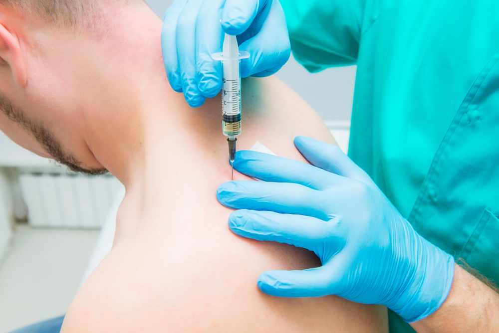 Doctor giving a close-up injection therapy (blockade)