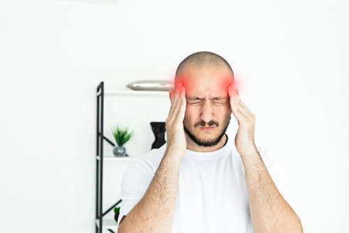 Person touching their forehead in discomfort, illustrating pain related to frontal headache causes.