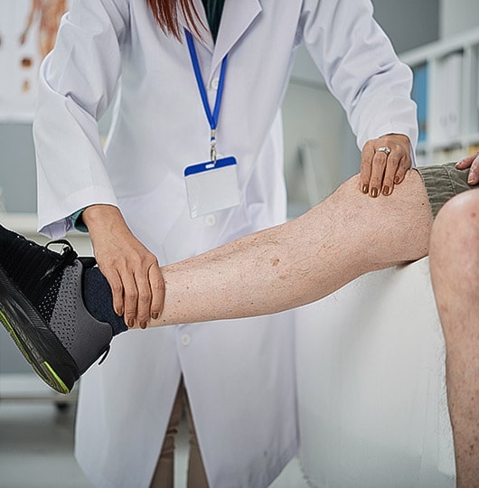 Doctor examining the veins on a patient’s leg.